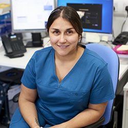 A photo of Christina Guevara, colleague of RCN Nurse of the Year 2023 Julie Roye, sitting at a desk wearing blue scrubs