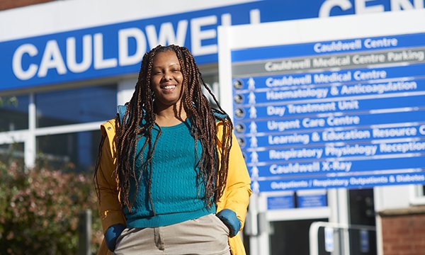 A picture of patient Joyce Tucker, smiling and looking relaxed with one hand in her pocket standing in front of Cauldwell Medical Centre, where she was part of the care improvement team set up by RCN Nurse of the Year 2023 Julie Roye