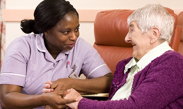 Picture shows a healthcare assistant with a care home resident. The pay of social care staff, including nurses, must be raised to help stabilise the sector in England, a health charity says