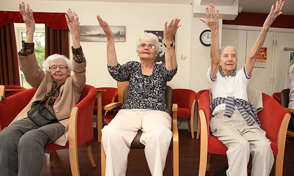 Picture shows three older women sitting in chairs with their arms raised in a group exercise session. A four-year project will build data resource on treatment and services at care homes.