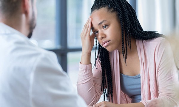 Picture shows a teenage girl sitting across a table across from a physician. The NHS rejects a think tank’s claim that more than one in four children and young people referred to specialist mental health services are rejected for treatment.