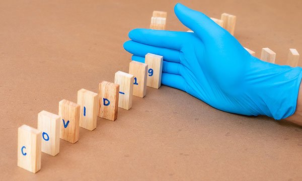 Picture shows a row of dominoes spelling out COVID-19