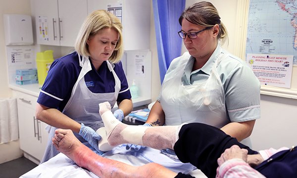 Practice nurse manager Emma Williamson and healthcare assistant Victoria Larkman treating a patient. Ms Williamson studied her practice’s leg ulcer care and devised a pathway that improved healing, reduced spending on dressings and freed up nurses’ time. 