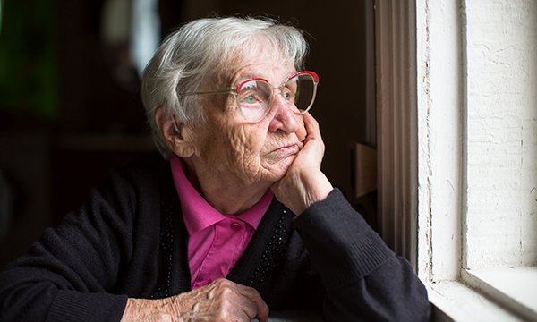 Picture of a lonely older woman looking out of a window