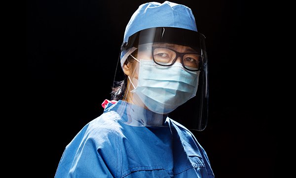 A nurse in PPE, wearing a visor, mask and gown