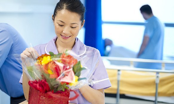 A nurse on a ward receiving a patient's gift of flowers 