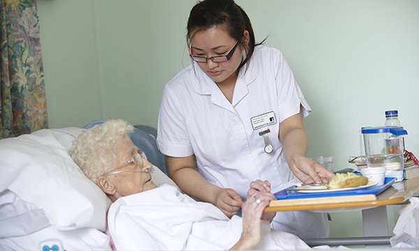 Picture of a nursing student caring for an older patient
