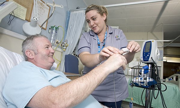 A nursing student helping a patient on a hospital ward