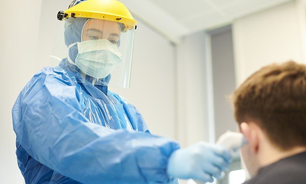 Picture shows a medic in protective clothing checking a boy's temperature. NICE is reviewing its critical care scale amid concerns that people with learning disabilities could be denied intensive care.