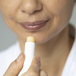 Picture shows woman applying lip balm