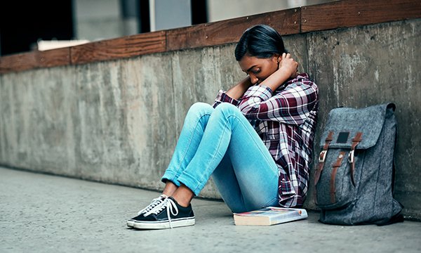 A young woman with a book and a satchel outside a building with her head in her hands. One in four student nurses leave before the end of their degree. Picture: iStock