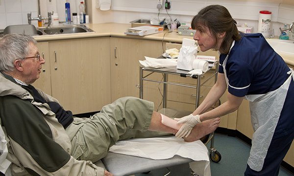 nurse care for man's leg wound in a practice setting