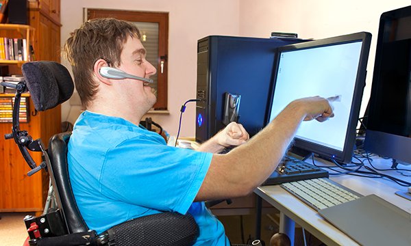 Image show young man with a learning disability using an adapted computer