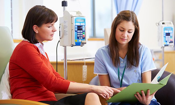 Picture shows a woman who has been having chemotherapy looking at test results with a nurse. This article reports on advice from health professionals on how cancer nurses can support patients with the menopause.