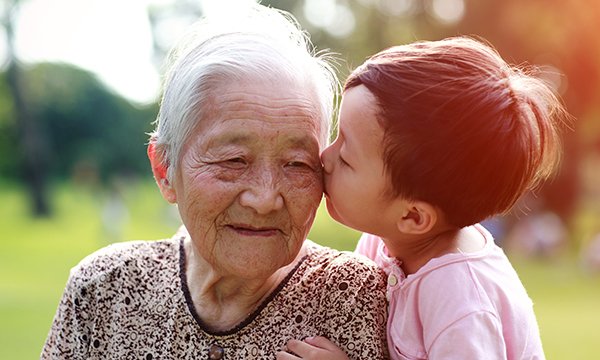 Picture shows a child kissing an older Asian woman. This article is by academics conducting a research project on what can be learned from care of older people in different cultures.