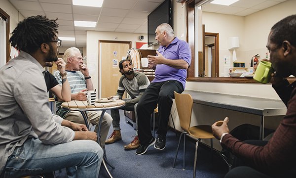 Picture shows a group of men talking to a mental health professional in a support group meeting. A community mental health framework for adults and older people will integrate mental health, physical health and social care services.