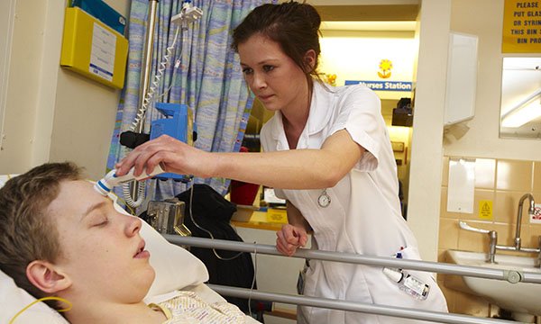 student tends to a teenage inpatient at the bedside