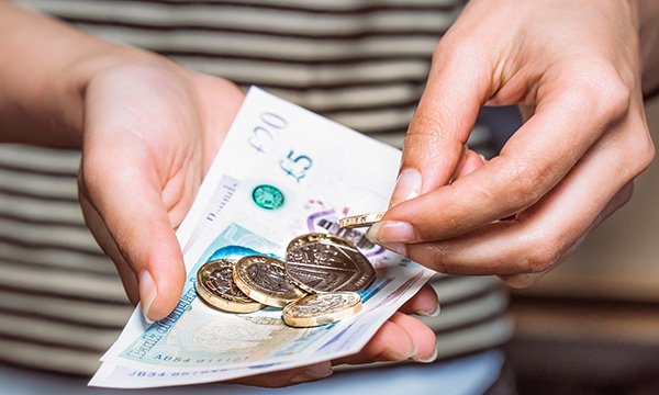 Picture shows someone counting cash. The article says nurses need to learn about personal health budgets, which allow patients to use NHS funding to purchase care outside traditionally commissioned services.