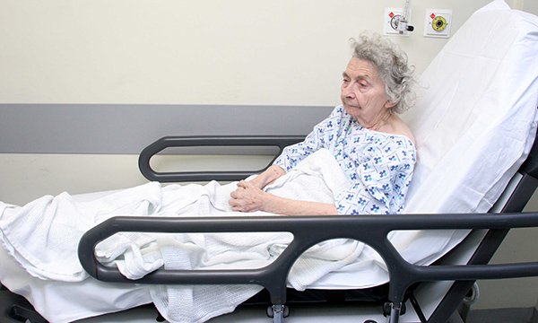 Older patient on trolley in corridor
