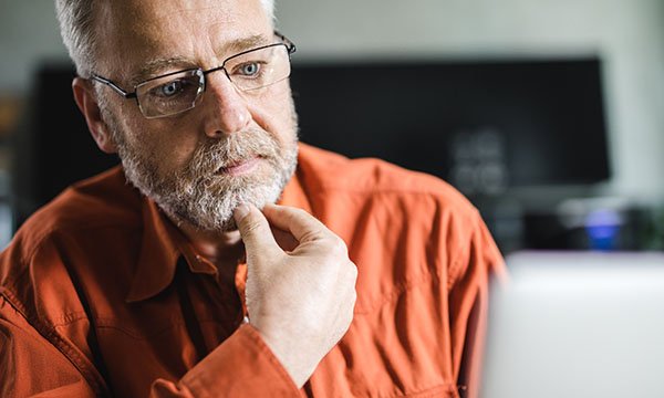Picture shows an older man appearing anxious while looking at a computer screen. Research by Macmillan shows thousands of people with cancer are left anxious, depressed or confused after finding misleading information online.
