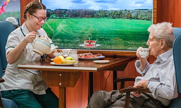 Occupational therapist Anna Tilney takes tea with a patient, who is dressed in his day clothes