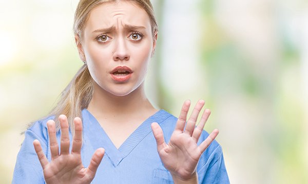 nurses looks frightened and holds her hands up defensively