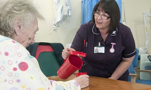 Nurse attending to an older patient who is experiencing and needs hydration