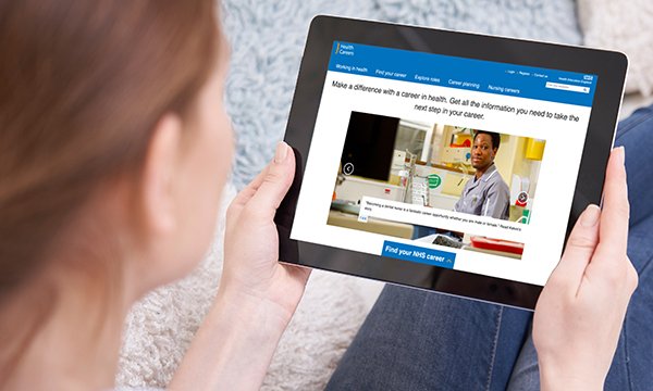 Picture shows a woman looking at an electronic tablet displaying a page about careers in healthcare.