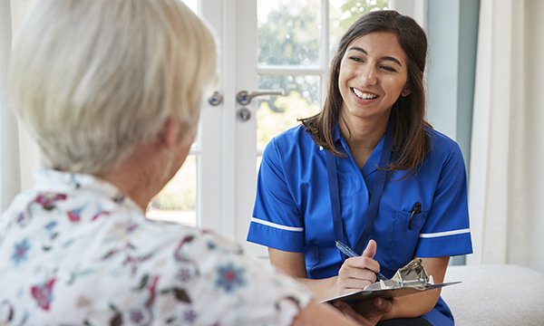 district nurse talks to patient during a home visit, as QNI announces rise in specialist practitioner qualifications