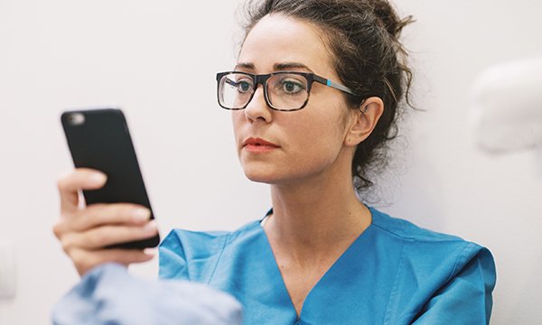 Picture portrays a nurse looking at a smartphone