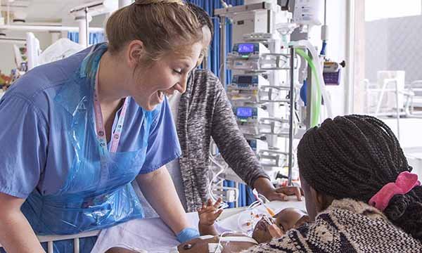 Picture shows a nurse in a paediatric intensive care unit caring for a baby who has had surgery