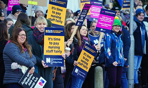 Striking nurses hold banners calling for better pay