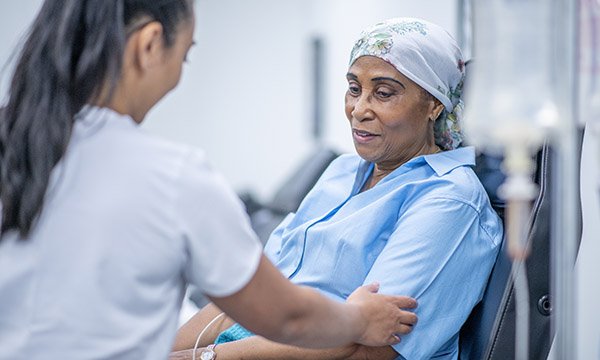 Nurse gently touches arm of woman who is having chemotherapy infusion