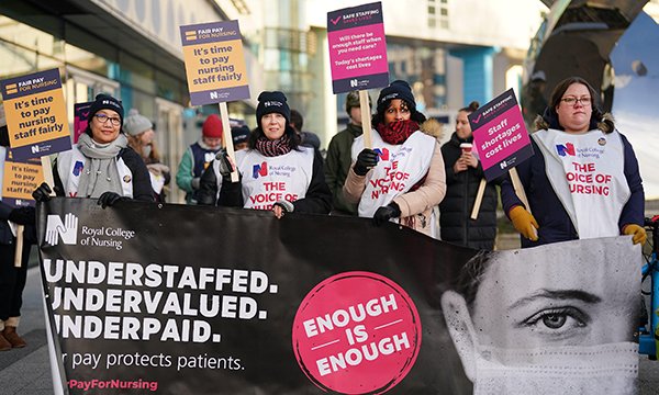 Line of nurses on strike in RCN pay dispute hold protest banner outside Queen Elizabeth Hospital in Birmingham