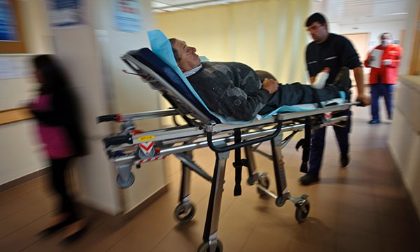 Photo of patient on trolley in busy NHS ward