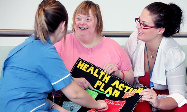 Photo shows nurse talking through a health action plan with a woman with learning disabilities and a family member: health promotion can be used collaboratively by nurses and people with learning disabilities to empower and reduce health inequalities