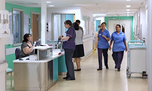 Staff at nurses’ station and walking along hospital corridor