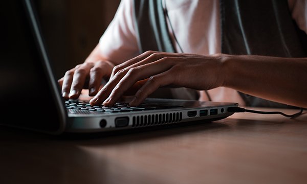 Close-up of hands typing on a laptop keyboard for a competency test