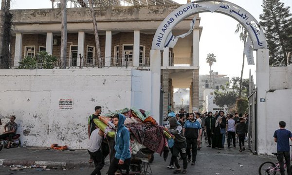Palestinians rescue usable items from the heavily damaged Al-Ahli al-Arabi Hospital building after bombing in Gaza City