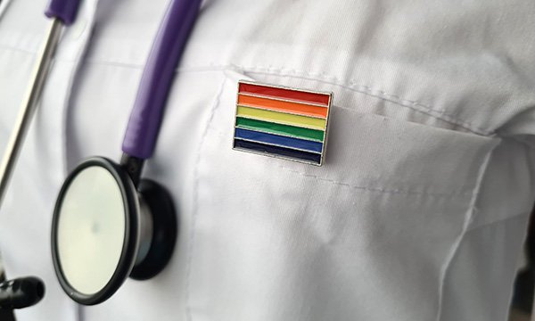 A nurse wearing a rainbow pin on their uniform to show their workplace is inclusive of LGBT+ people’s needs