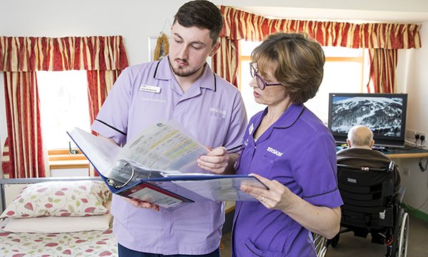 Nursing in a care home look at documents in a folder together
