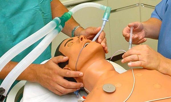 Nursing students learn how to insert and attach an oral tube into a manikin