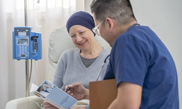 A nurse explains a document being held by a smiling female cancer patient