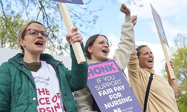 Nurses on picket line wave banners during their NHS pay strike