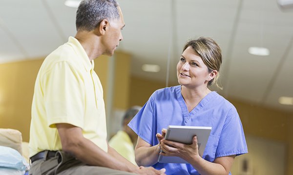 A nurse with a tablet handset talking to a patient