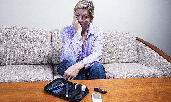 Woman looks in distress at her insulin kit