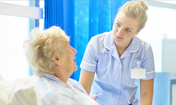 nurse talks to patient at bedside