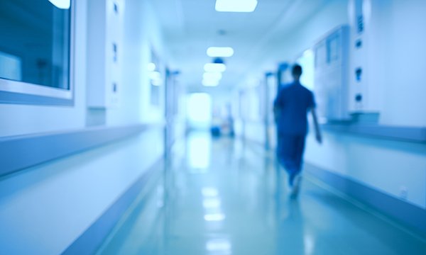 lone healthcare worker walks down corridor