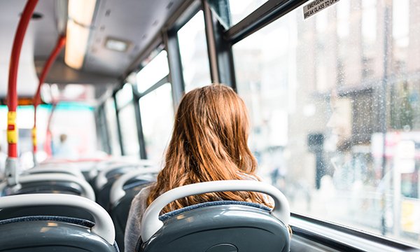 woman sits alone on top deck of a bus