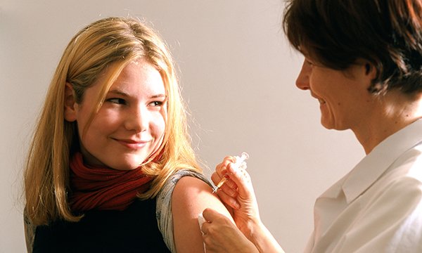 A young woman being vaccinated by a nurse